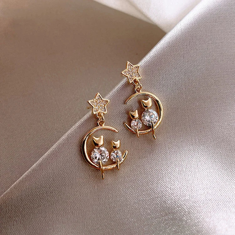 Goldene Ohrringe mit Katzen, Mond und Sternen, verziert mit Kristallen, eleganter Schmuck.