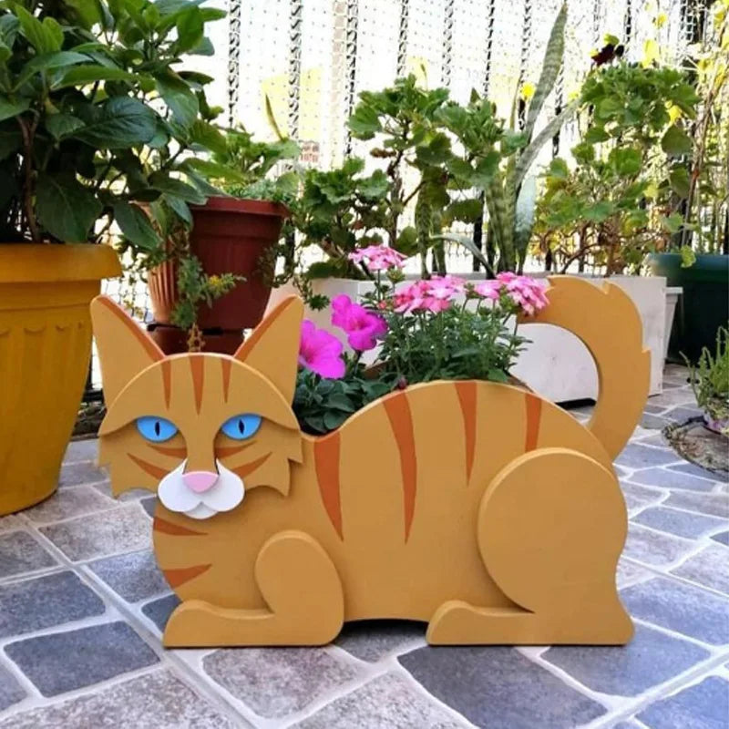 Katzenförmiger Pflanztopf aus Holz, Garten-Dekoration, braun, mit rosa Blumen, auf Terrasse.