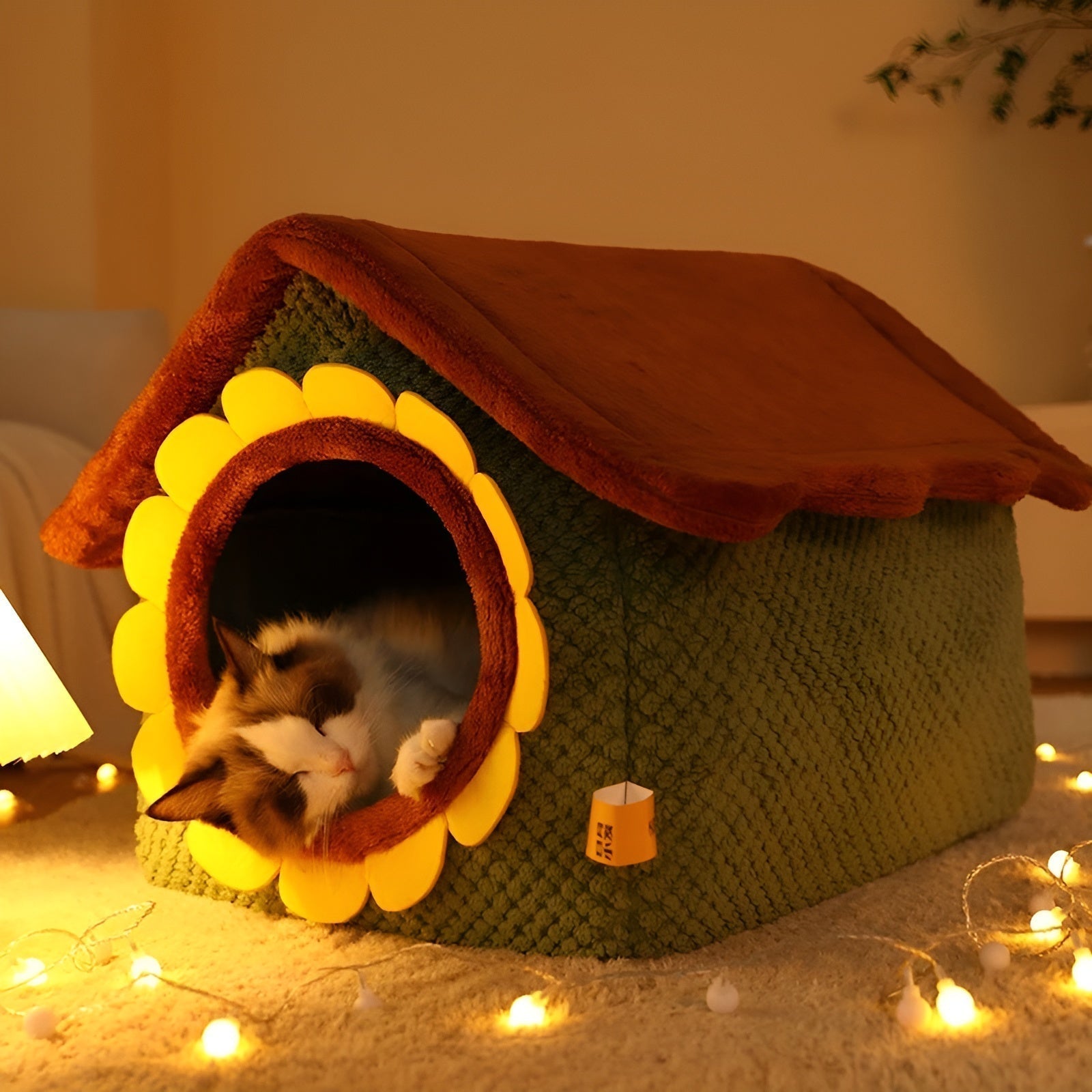 Katzenhaus aus Stoff in Form eines Häuschens, grün mit gelbem Blütenrahmen, gemütlich beleuchtet.