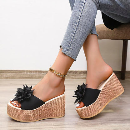 Schwarze Plateau-Sandalen mit Blumen, Damen, Keilabsatz, Sommermode, Jeanshintergrund.