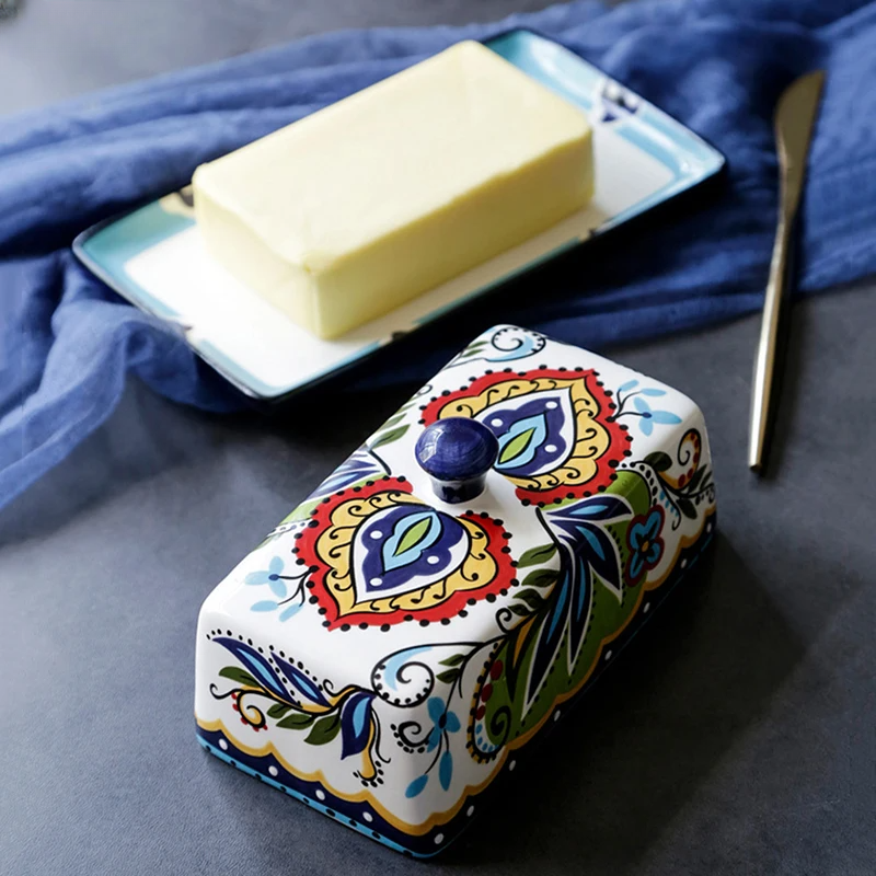Keramik-Butterdose mit buntem Blumenmuster, rechteckig, auf grauem Tisch.