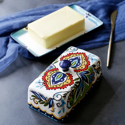 Keramik-Butterdose mit buntem Blumenmuster, rechteckig, auf grauem Tisch.