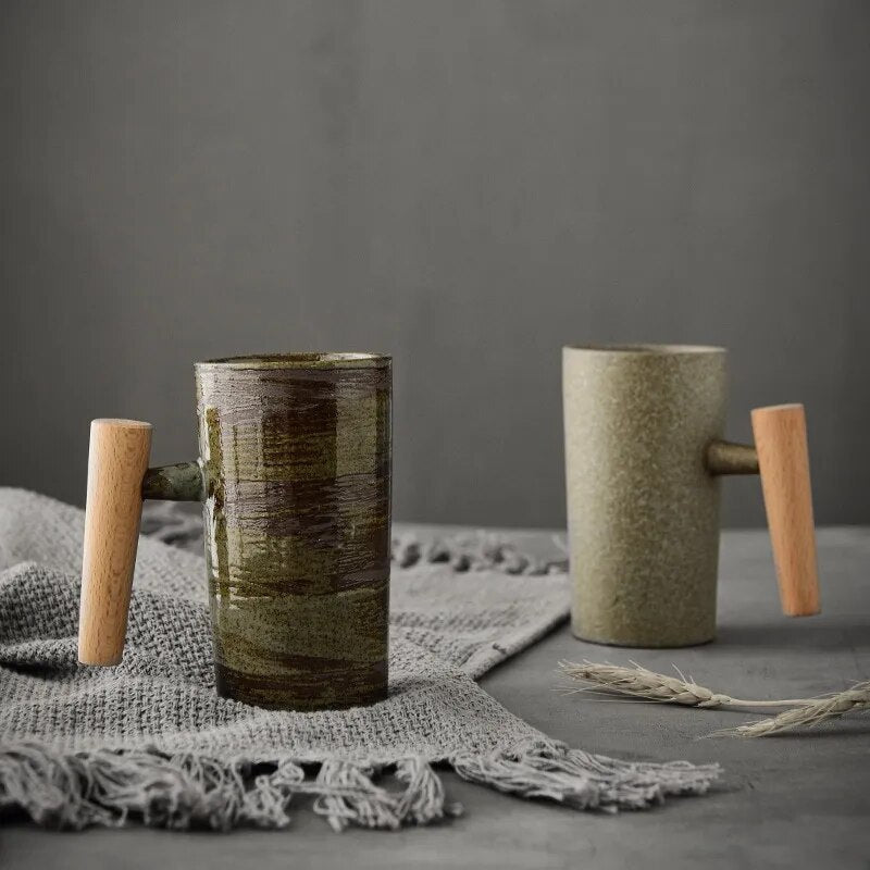 Zwei Keramiktassen mit Holzgriffen auf grauem Tuch, modern, skandinavisches Design.