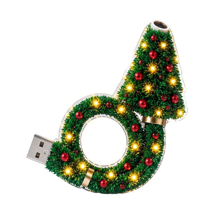 Projektorn fristĂĽende pĂĽ vit bakgrund, med grĂ¶na grenar, rĂ¶da kulor, varma lysdioder, guldringar och USB-kontakt till vĂ¤nster. 1