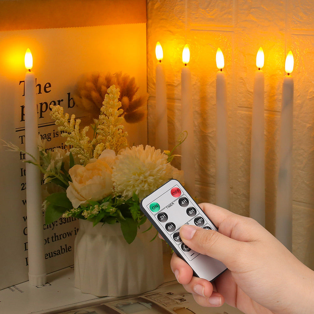 Hand hält Fernbedienung vor LED-Kerzen und Blumenarrangement, warmes Licht, gemütliche Atmosphäre.