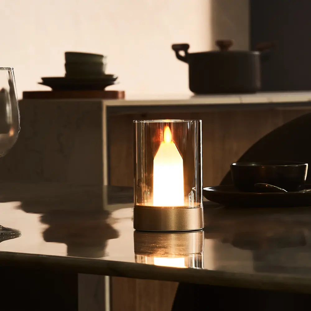 LED-Kerze in Glaszylinder auf Tisch, warmes Licht, moderne Dekoration, gemütliche Atmosphäre.