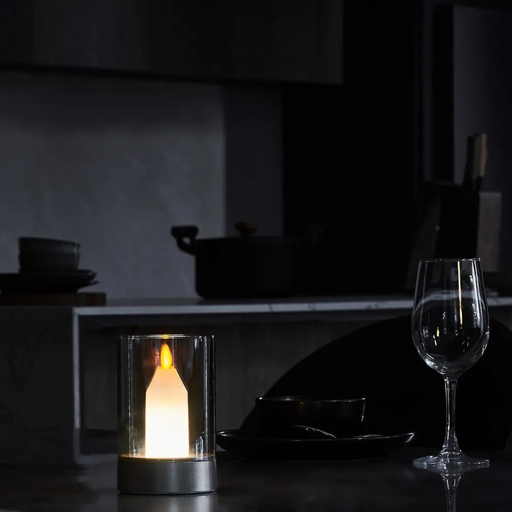 LED-Kerze in Glaszylinder, warmweißes Licht, moderne Tischdekoration, dunkler Hintergrund.