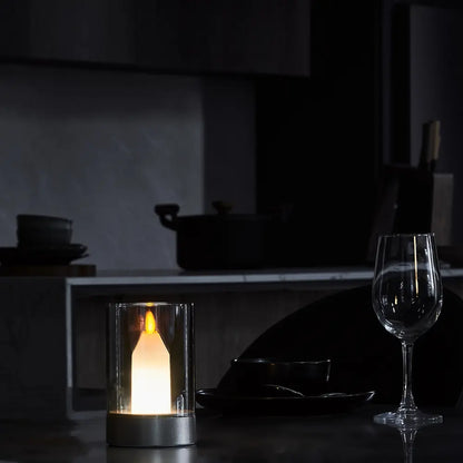 LED-Kerze in Glaszylinder, warmweißes Licht, moderne Tischdekoration, dunkler Hintergrund.