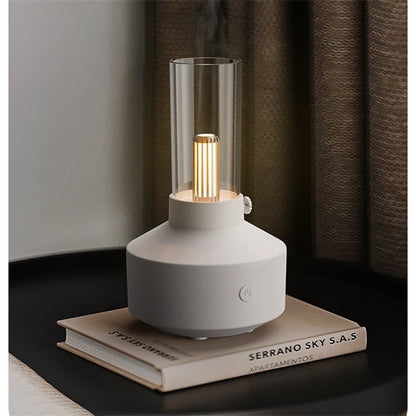 Aromatherapie-Diffuser mit Kerzenlicht, weiß, Glaszylinder, auf Buch, modernes Design.