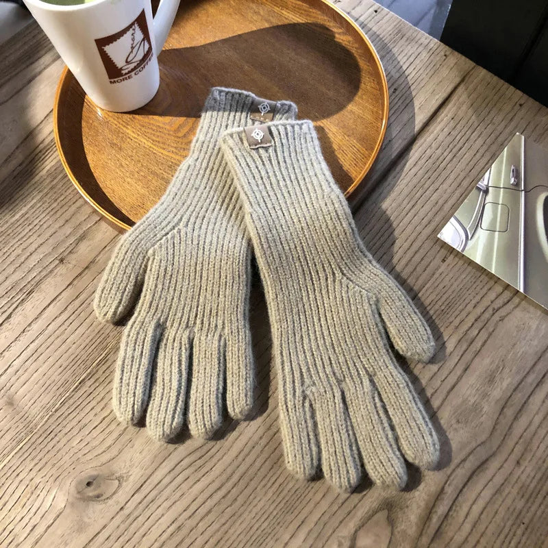 Beige Strickhandschuhe aus Wolle auf Holztisch, winterliche Accessoires, warme Bekleidung.