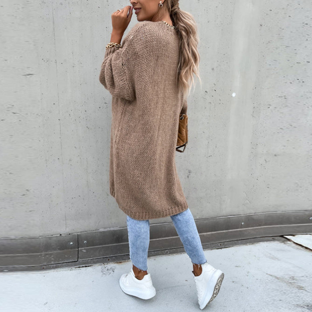 Frau in khaki Strickjacke, blaue Jeans, weiße Sneaker, lässiger Herbstlook, Straßenmode.