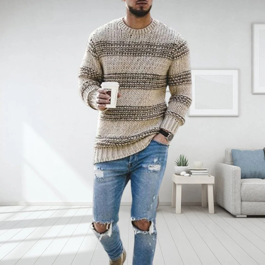 Mann in gestreiftem Strickpullover und zerrissenen Jeans, hält Kaffeetasse, moderne Wohnung.