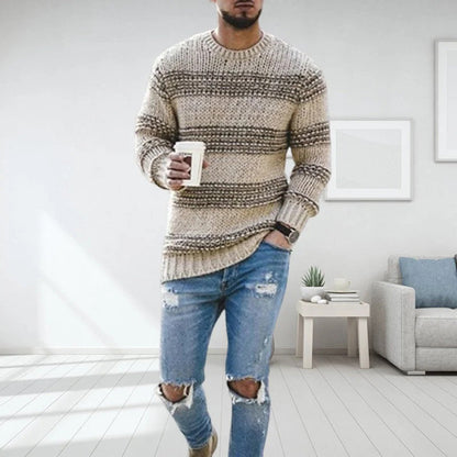 Mann in gestreiftem Strickpullover und zerrissenen Jeans, hält Kaffeetasse, moderne Wohnung.