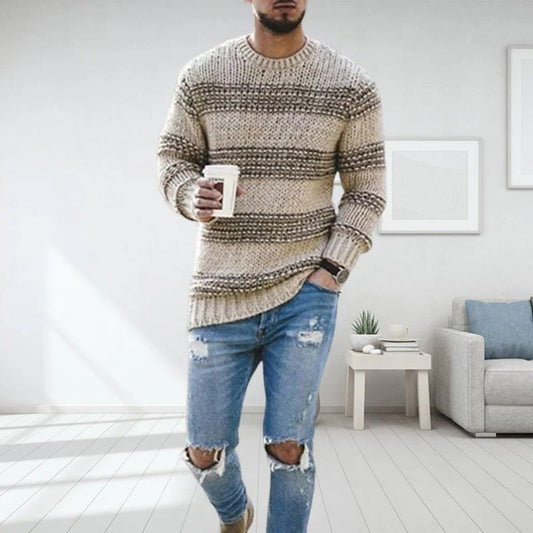 Mann in gestreiftem Strickpullover und zerrissenen Jeans, hält Kaffeetasse, moderne Wohnung.