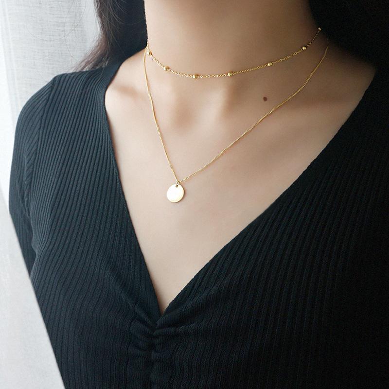 Frau trägt goldene Boho-Halskette mit Münzanhänger, mehrlagig, 925 Sterling Silber, modisch.