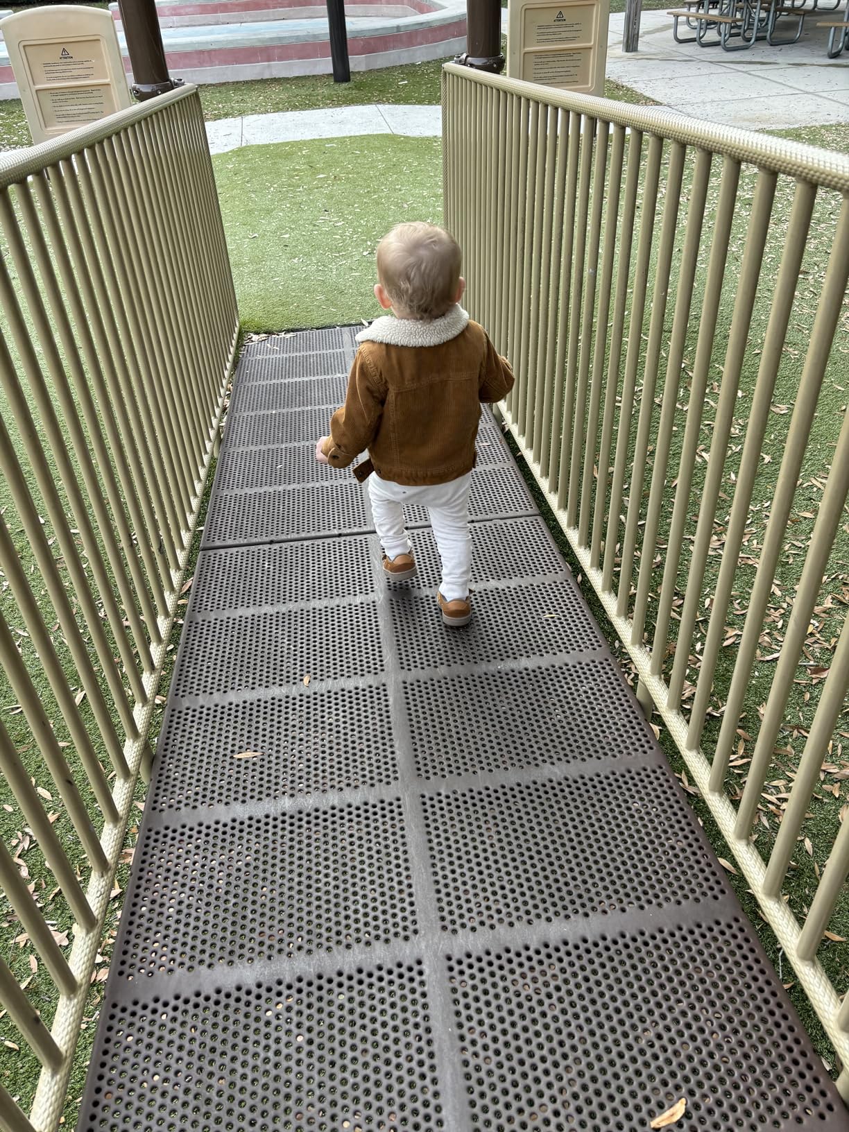 Kleinkind in brauner Jacke auf Spielplatzbrücke, Herbstmode, Outdoor-Aktivität, Kinderspielplatz.