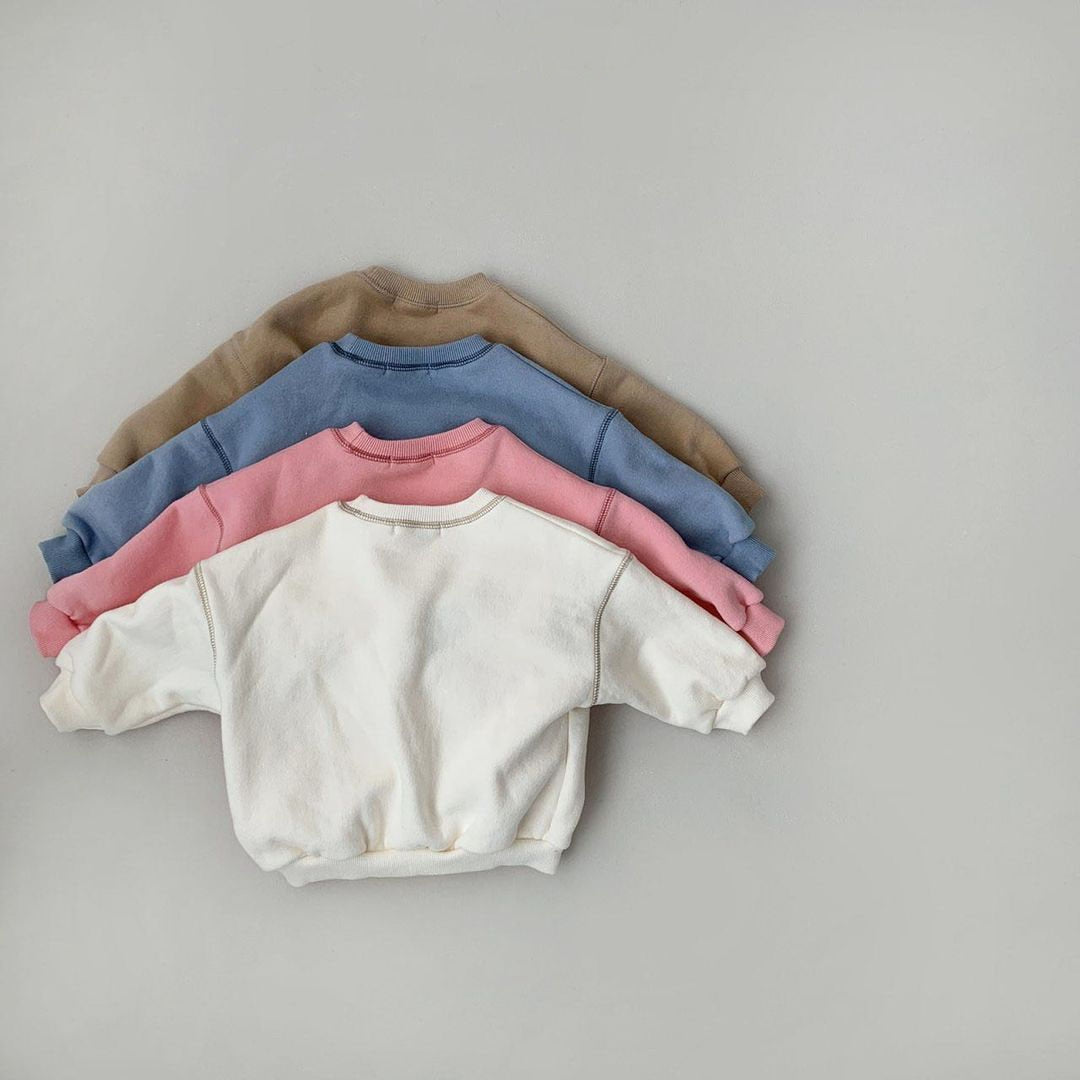 Fünf Baby-Sweatshirts in Beige, Blau, Rosa, Weiß auf grauem Hintergrund, Baumwolle, unisex.