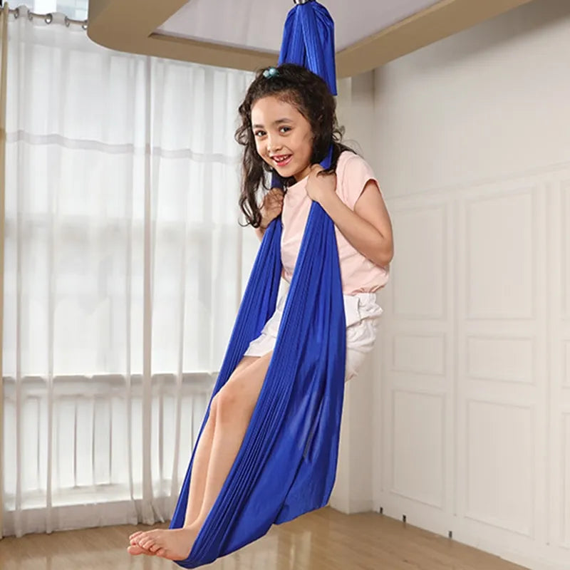 Mädchen in blauem Therapieschaukel, Indoor-Spielzeug, sensorische Integration, Entspannung.