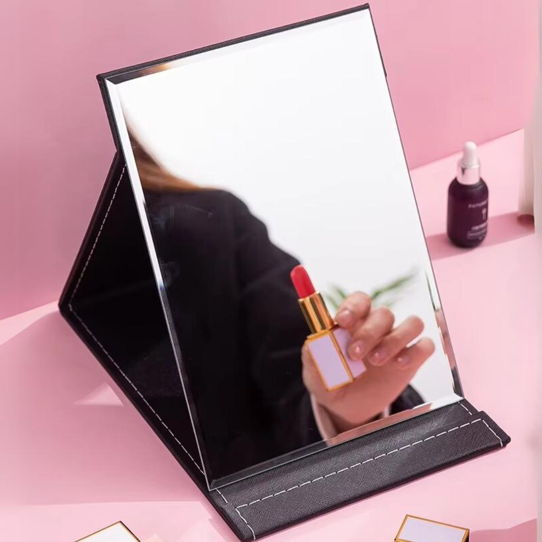 Faltbarer Schminkspiegel mit rotem Lippenstift auf rosa Hintergrund, ideal für Make-up.