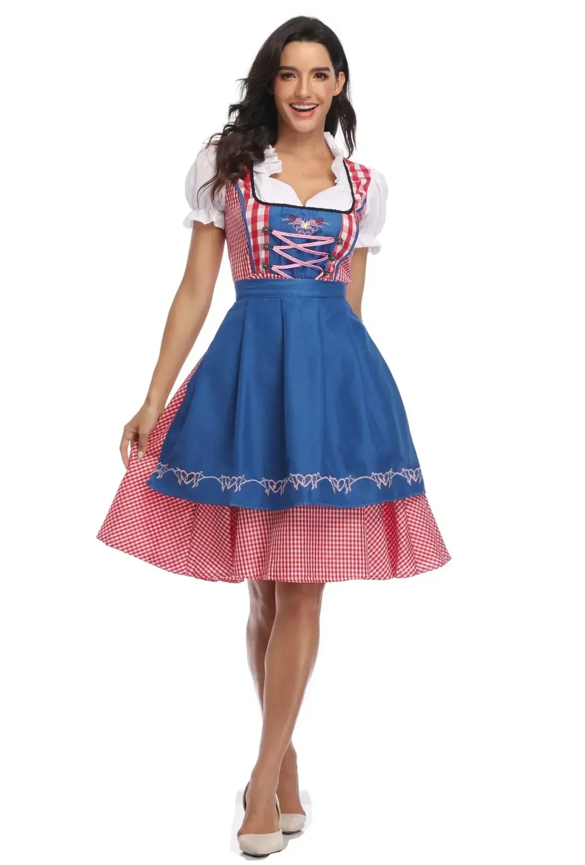 Modell i rödrutig dirndlklänning med blått broderat förkläde och rosa snörning, helbild framifrån. 7