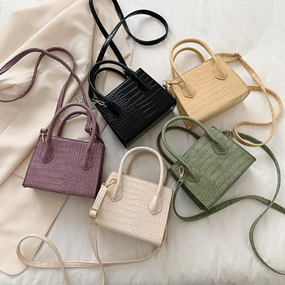 Fünf Mini-Handtaschen aus Kunstleder in verschiedenen Farben auf weißem Hintergrund.