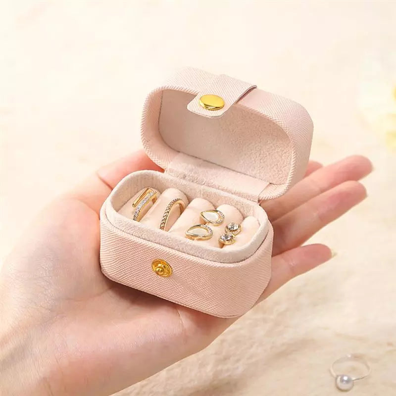 Rosa Schmuckkästchen aus Samt mit Ringen, tragbar, handgehalten, ideal für Reisen.