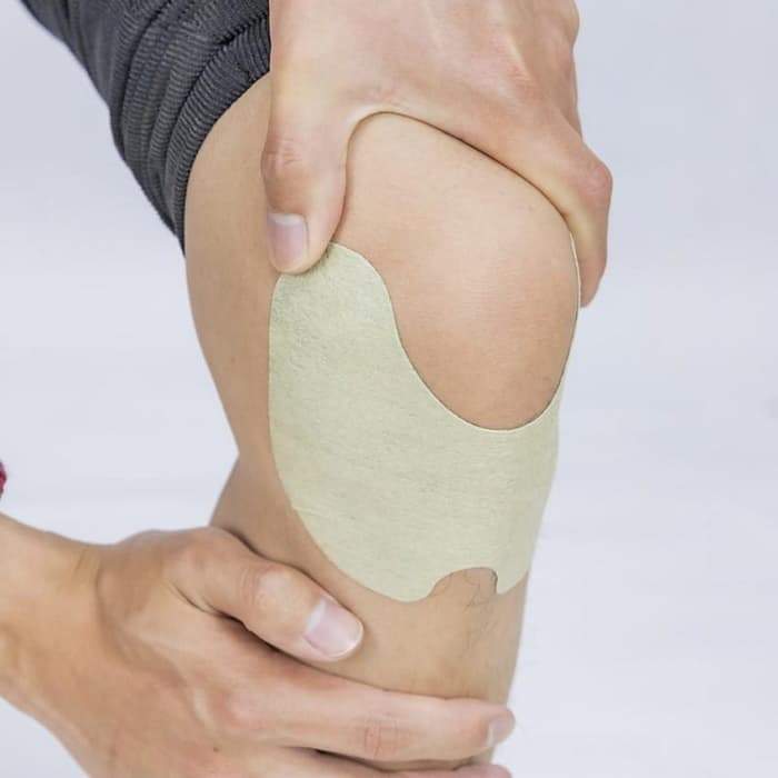 Person legt Kniebandage auf, beige, Schmerztherapie, Unterstützung, Gelenkschutz, Sportverletzung.