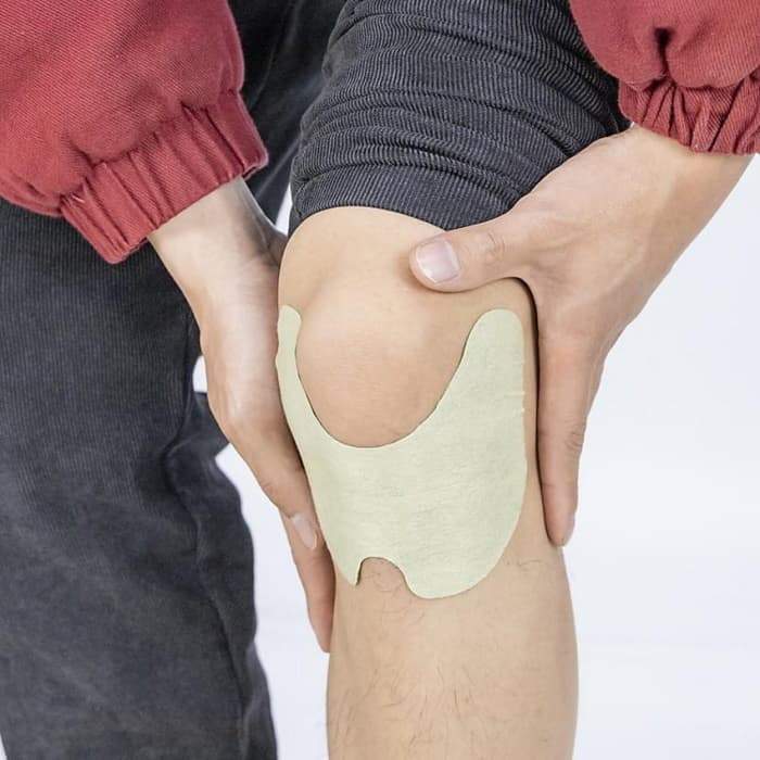 Person mit Kniebandage, beige, Schmerztherapie, Unterstützung, Gelenkschutz, Sportbekleidung.