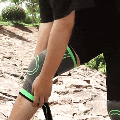 Person trägt graue Kniebandage mit grünen Akzenten, Outdoor, Sport, Unterstützung, Kompression.