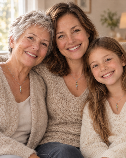 Tre generationer, mormor, mamma och dotter, sitter tätt ihop i soffan och bär alla samma halsband med kramhänge. 5
