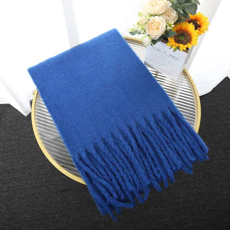 Blaue Kaschmirdecke mit Fransen auf Tisch, dekoriert mit Blumen, luxuriöses Wohnaccessoire.