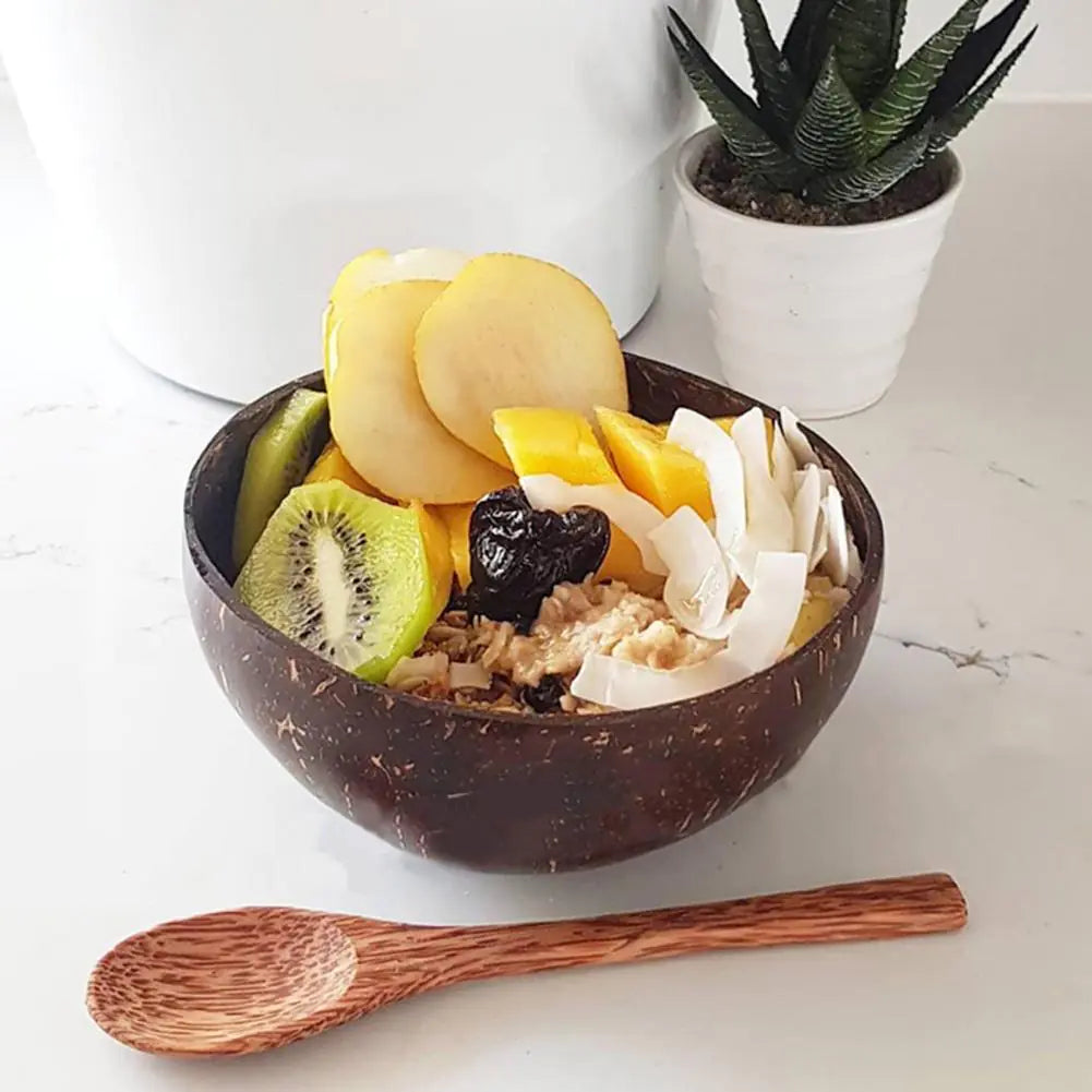 Kokosnuss-Schüssel mit Haferflocken, Kiwi, Apfel, Mango, Pflaume und Kokoschips auf Marmortisch.