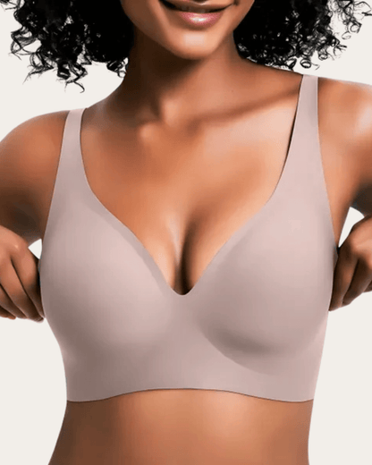 Modell bär slät bralette i ljus gråbeige nyans med V-ringning, sedd framifrån. 10