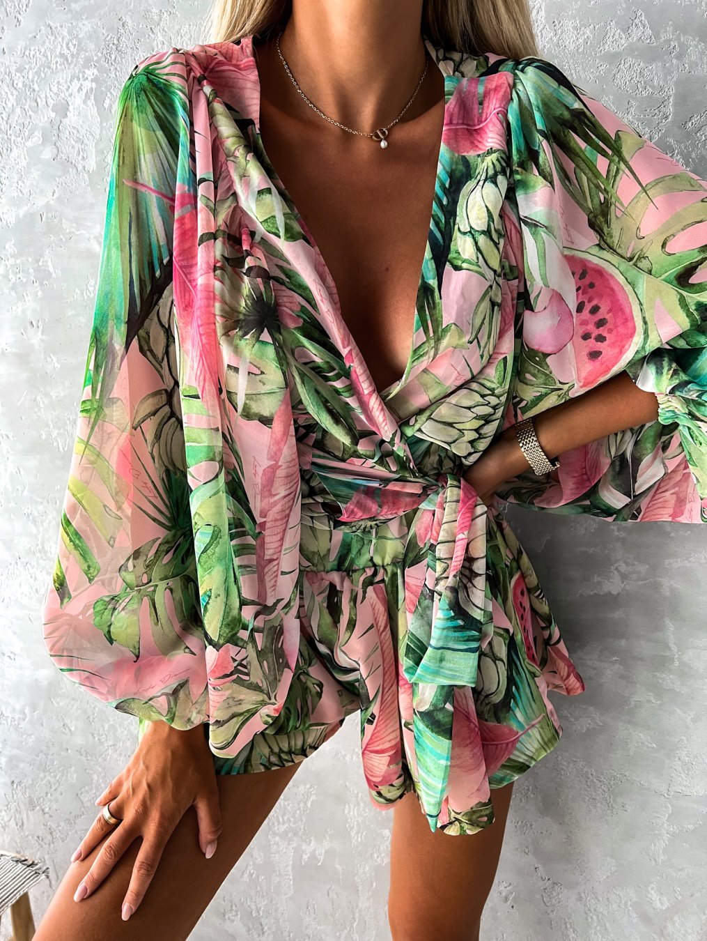 Frau in grün-rosa Sommerkleid mit tropischem Muster, V-Ausschnitt, lange Ärmel, modisch.