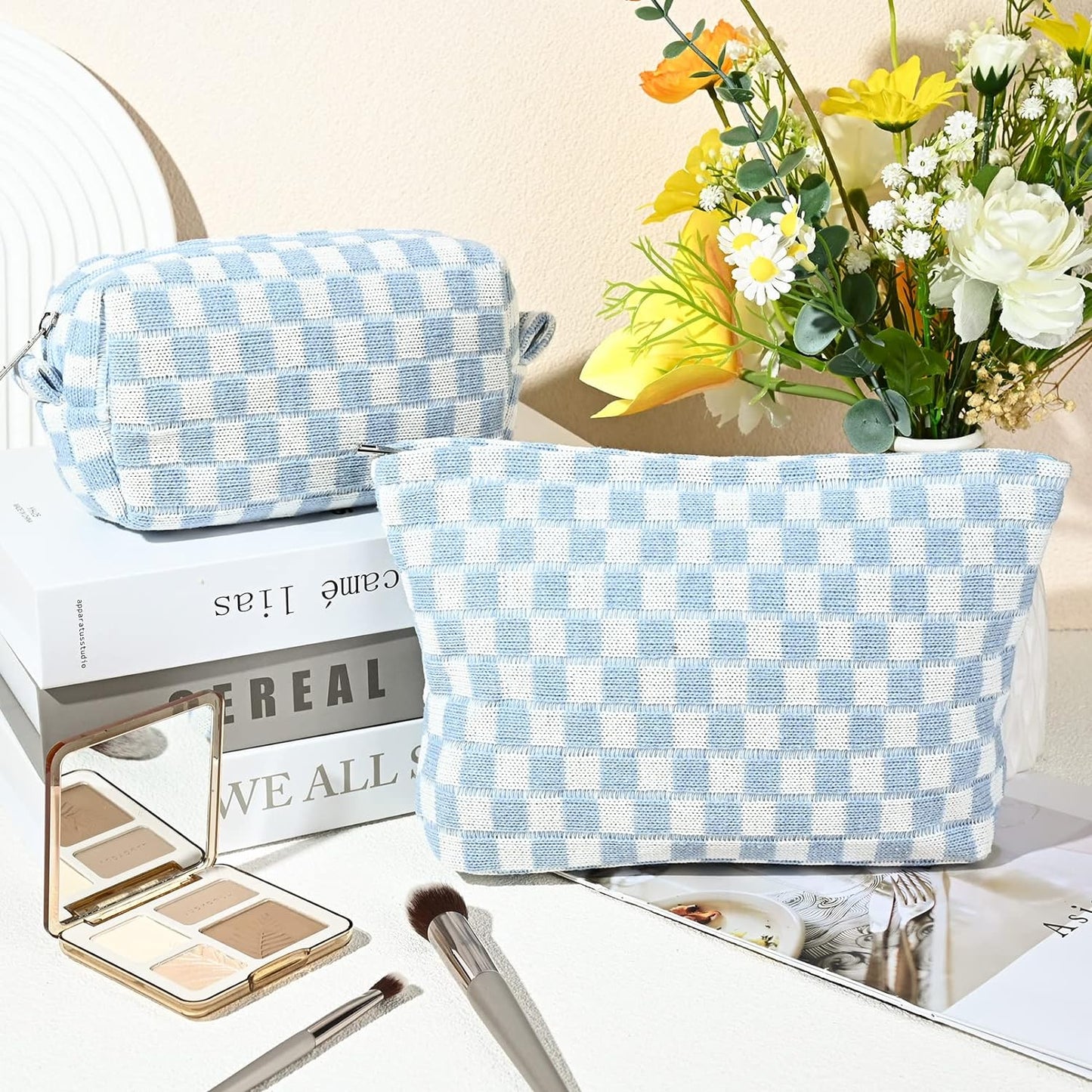 Hellblau-weiß karierte Kosmetiktasche aus Stoff, neben Blumenstrauß und Make-up-Pinsel.