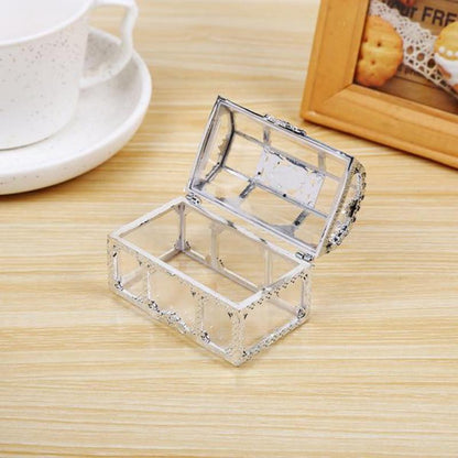 Transparente Schmuckschatulle aus Glas, rechteckig, auf Holztisch, geöffnet, dekorativ.