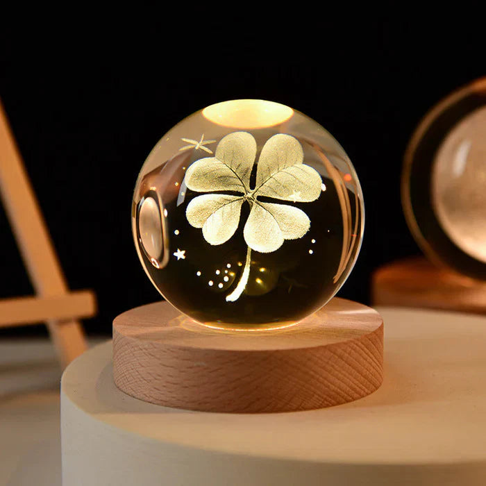 Kristallkugel mit beleuchtetem vierblättrigem Kleeblatt auf Holzsockel, dekorative LED-Lampe.