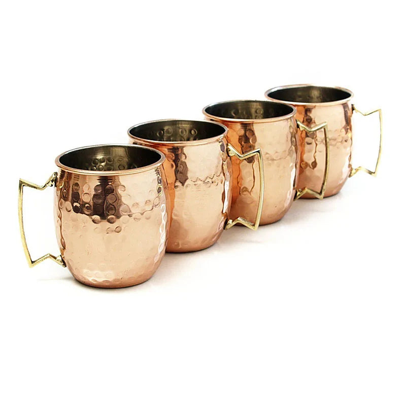 Vier gehämmerte Kupferbecher mit goldenen Griffen, ideal für Moscow Mule Cocktails.