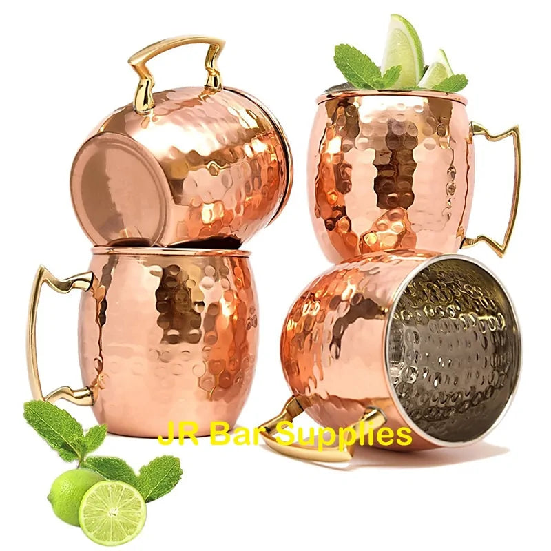 Vier gehämmerte Kupferbecher mit Griffen, ideal für Moscow Mule Cocktails, mit Limetten und Minze.