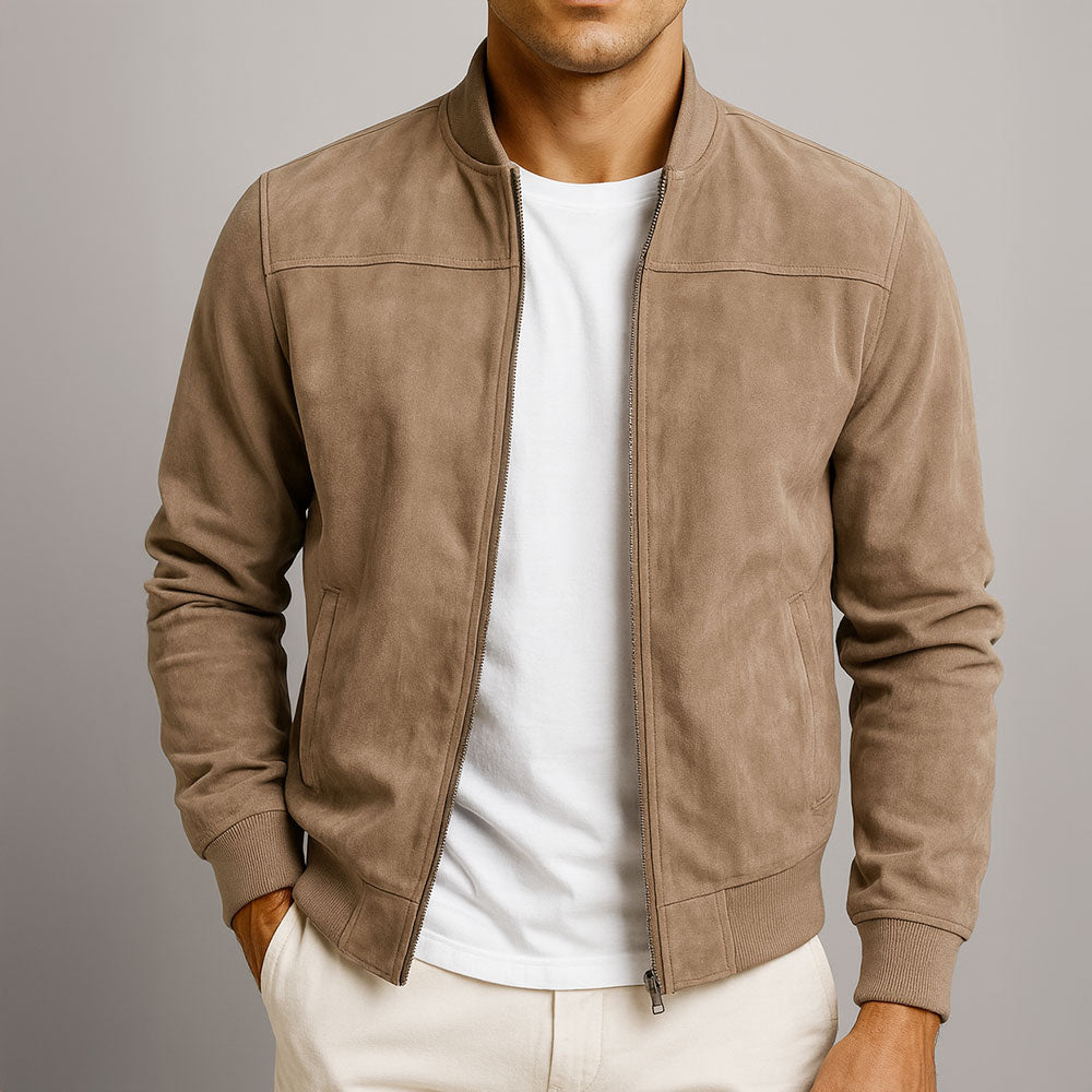 Man i beige mockajacka med öppen dragkedja, vit t-shirt och ljusa byxor, högra handen i fickan, framifrån i närbild. 1