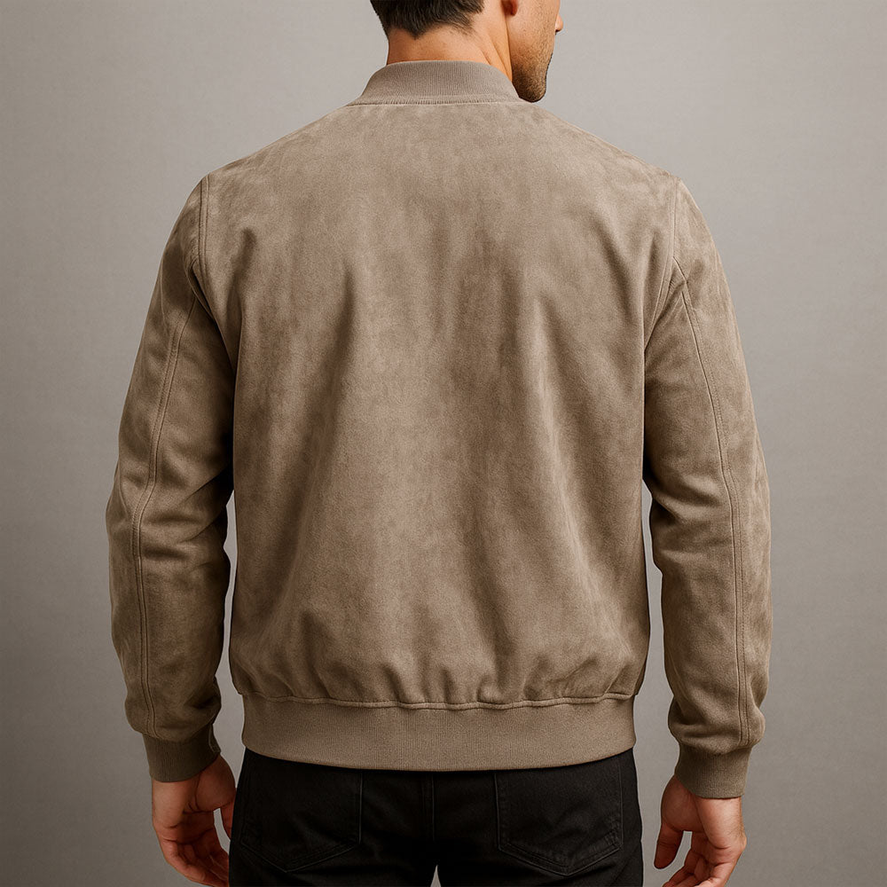 Jackan i beige mocka sedd bakifrån på en man i svarta byxor, med ribbad krage, ribbad nedre kant och muddar. 7