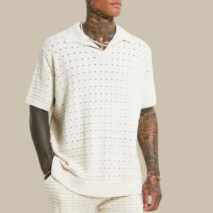 Mann in cremefarbenem Strick-Poloshirt, kurzärmelig, modern, lässig, tätowiert.