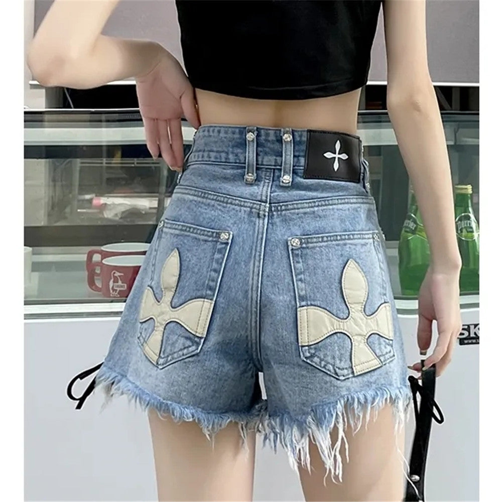 Frau in blauen Jeansshorts mit weißen Kreuzmotiven, schwarzes Top, modisch, Sommerkleidung.