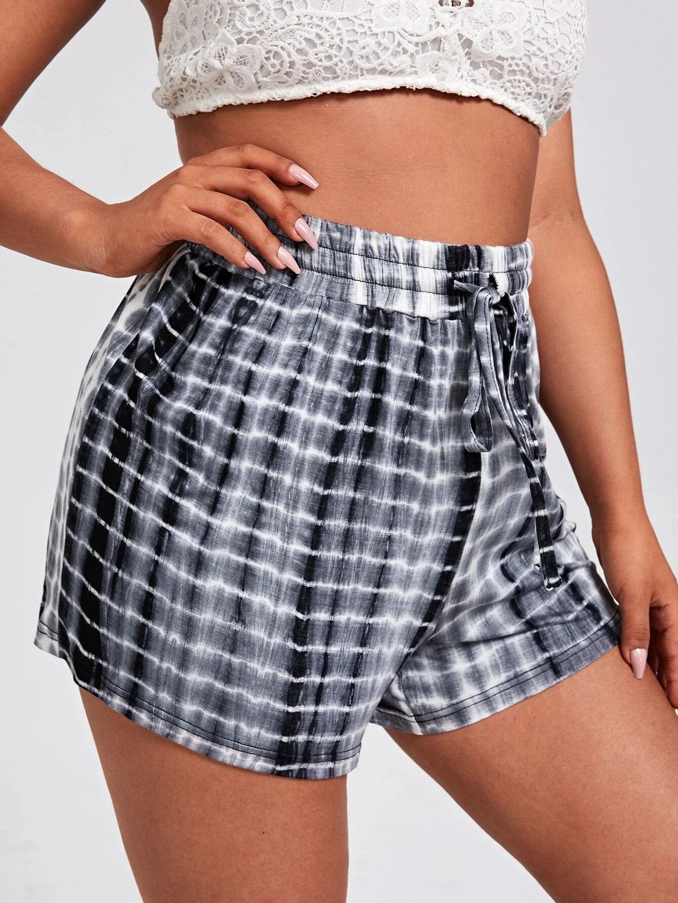 Frau in schwarz-weiß karierten Shorts und weißem Spitzen-BH, Sommermode, Freizeitkleidung.