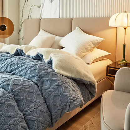 Luxuriöses Bett mit blauer Steppdecke, beigen Kissen und Nachttischlampe im modernen Schlafzimmer.