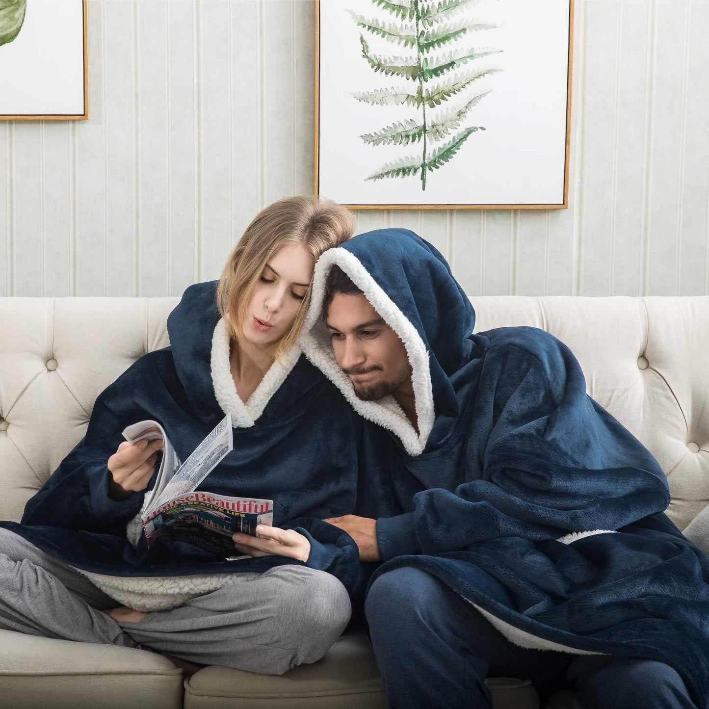 Paar in blauen Kuscheldecken auf Sofa, gemütlich, lesen Zeitschrift, Wohnzimmer, Winter.