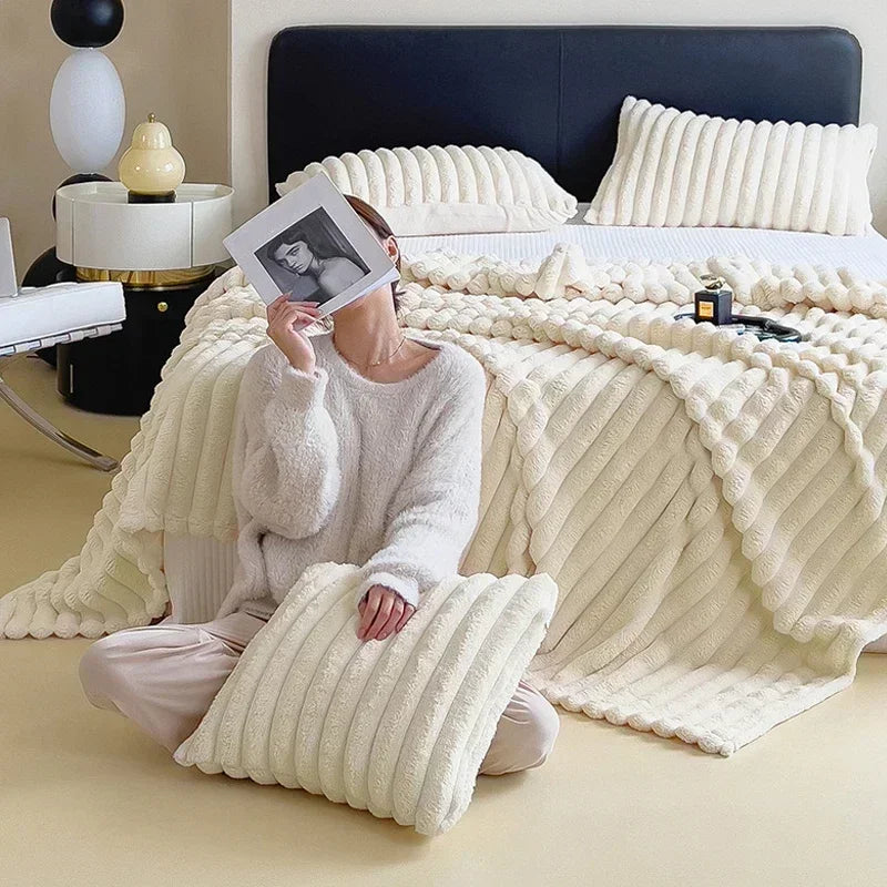 Flauschige cremefarbene Bettdecke und Kissen-Set aus Strickstoff auf modernem Bett.