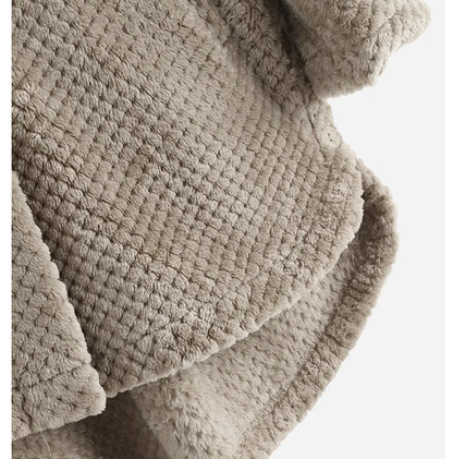 Beigefarbene, flauschige Decke aus Kunstfell, ideal für gemütliche Wohnräume.