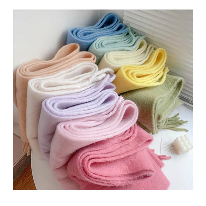 Weiche, bunte Wollschals in Pastellfarben auf weißem Tisch, modische Accessoires.