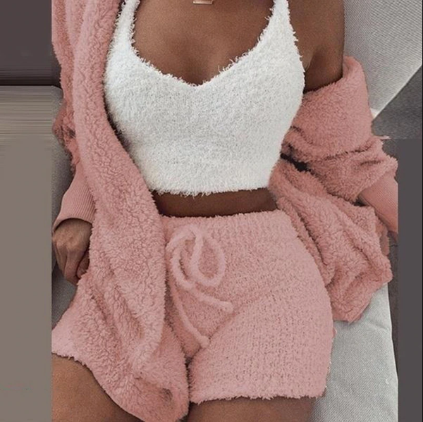Frau in rosa flauschigem Lounge-Set, bestehend aus Shorts, Top und Cardigan, auf Sofa.